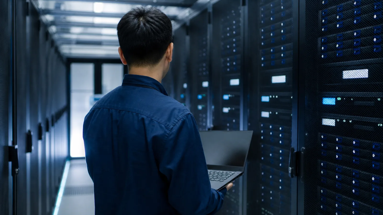 机房走廊内,IT 管理员用笔记本检查机柜